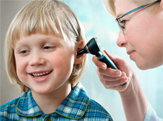 A hearing care professional examining a child’s ear